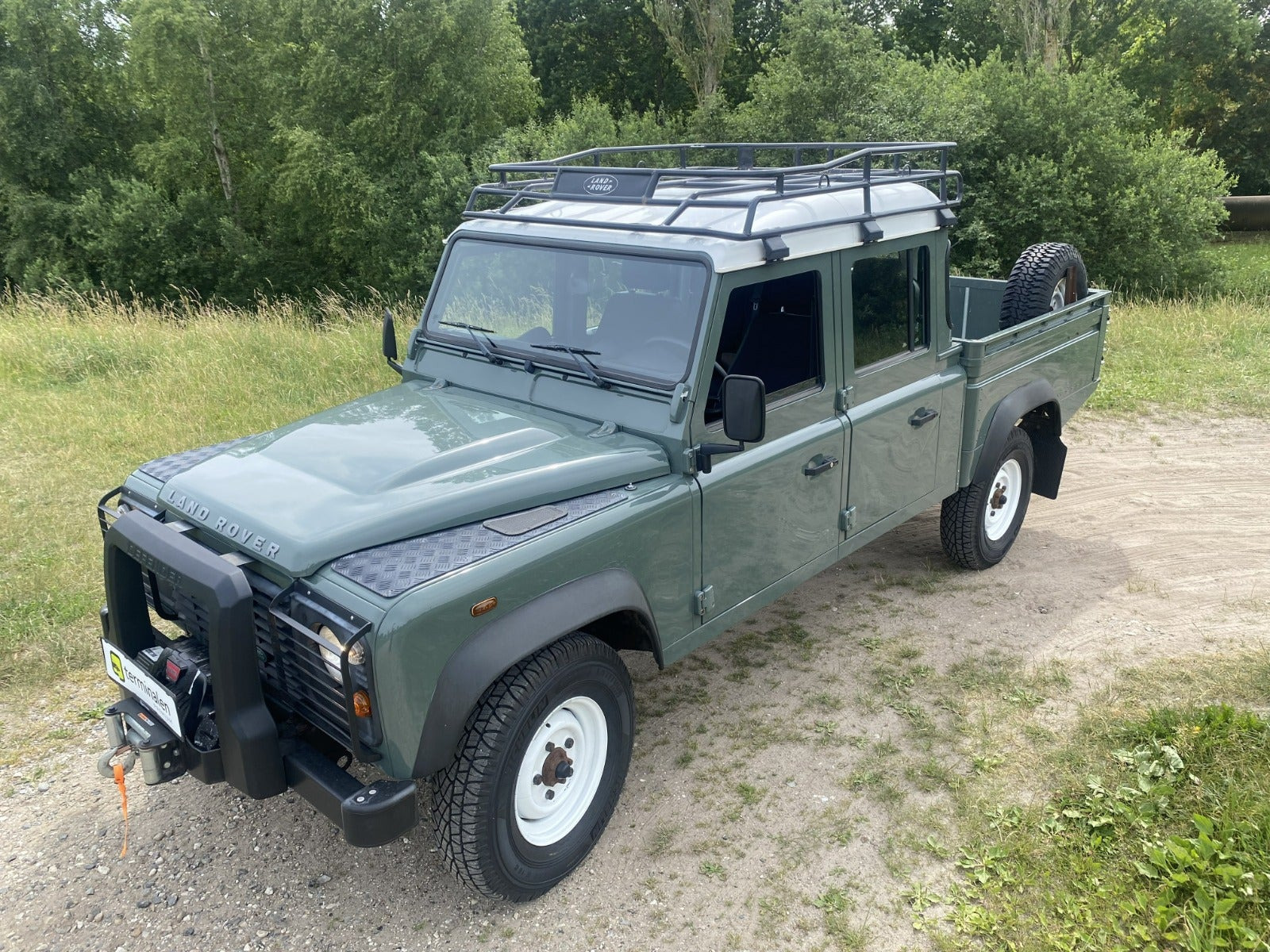 Grøn Land Rover Defender 130 fra 2013 set udefra