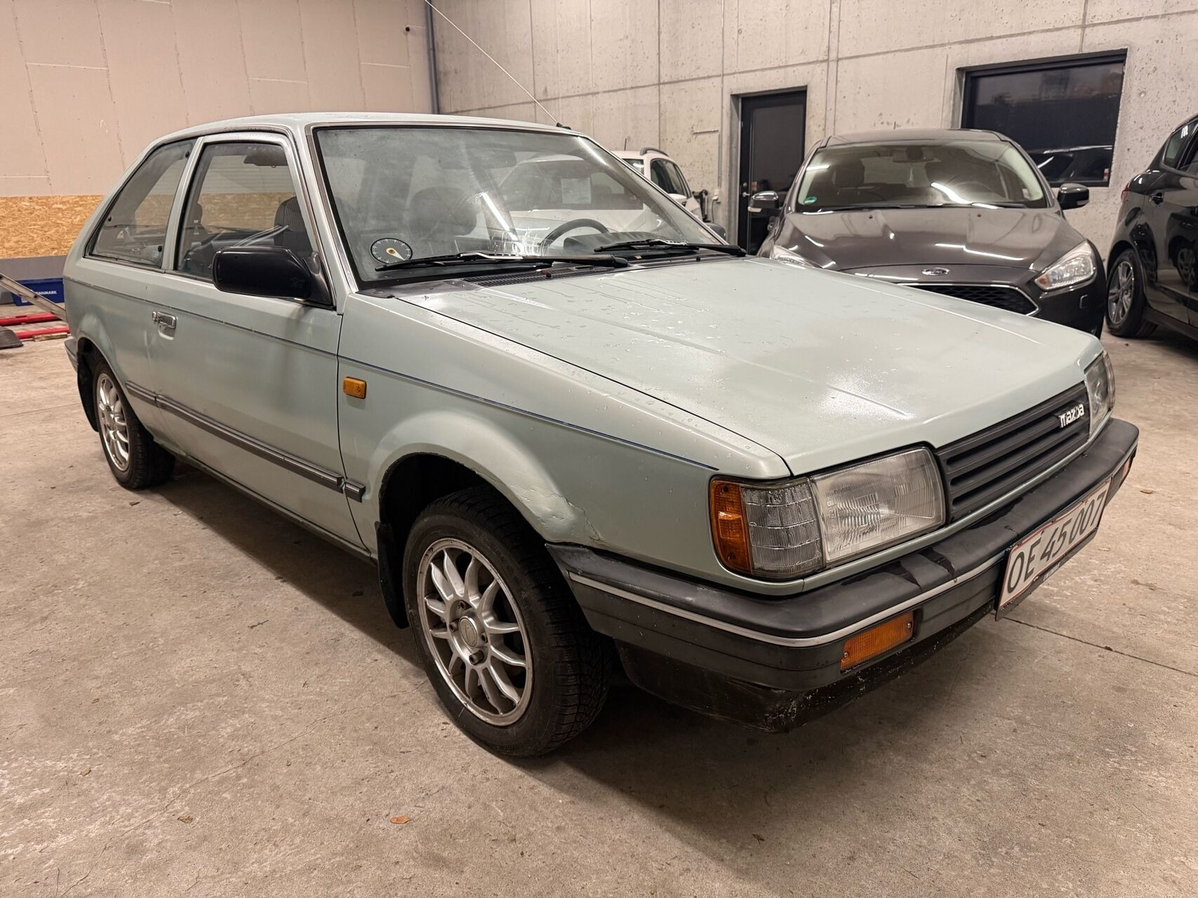 Blå Mazda 323 fra 1987