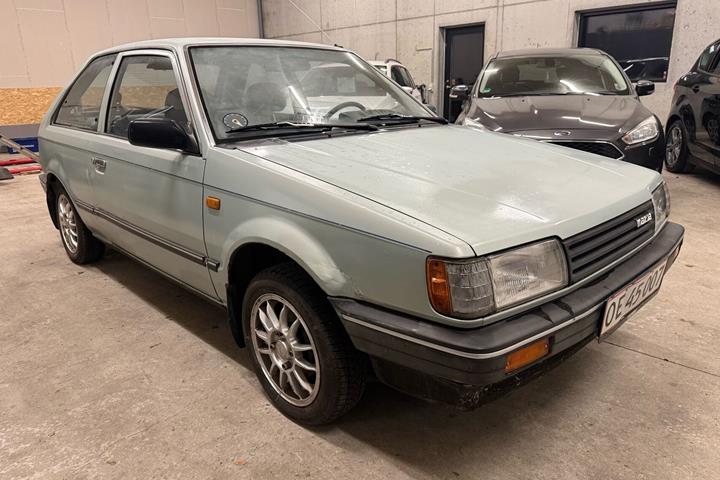 Blå Mazda 323 fra 1987